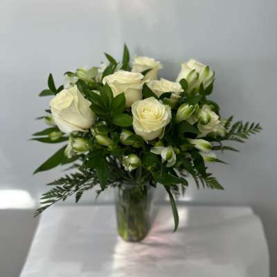 White roses and buds arranged in a clear glass vase