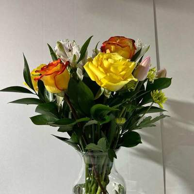 Bouquet of yellow and orange roses in a clear glass vase