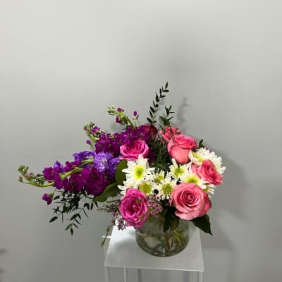 Pink and purple flower arrangement in a clear glass vase