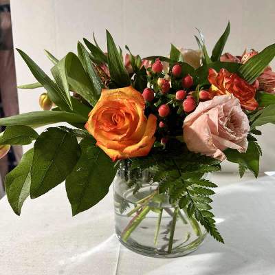 Orange and blush roses in a clear glass vase