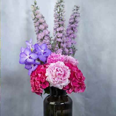 Pink and purple flowers arranged in a dark glass vase