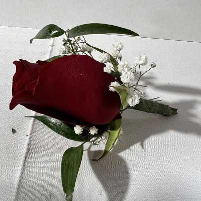 Red rose boutonniere with white baby's breath and green leaves