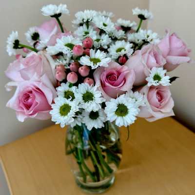 Pink roses and white daisies arranged in a clear glass vase
