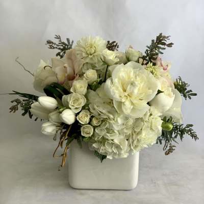 White floral arrangement in a square ceramic vase