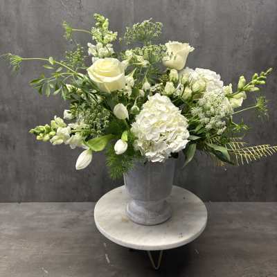 White roses and hydrangeas arranged in a gray urn