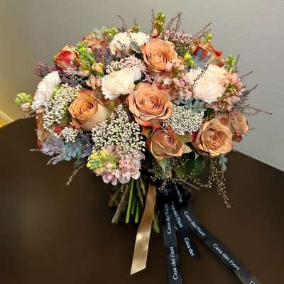 Peach roses and white blooms arranged in a hand-tied bouquet