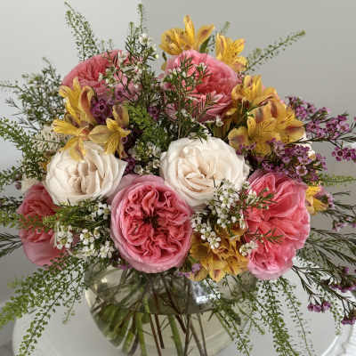 Pink and white roses with yellow flowers in a glass vase