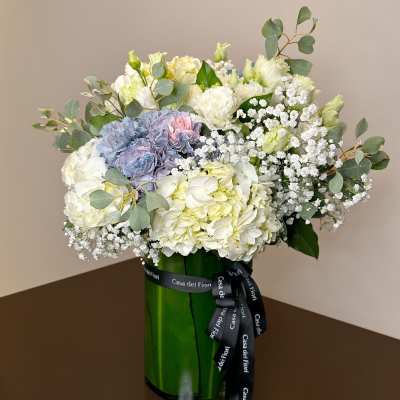Bouquet of white and pale blue flowers in a green glass vase