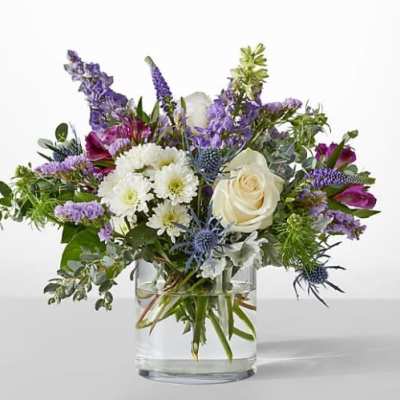 Mixed bouquet of white and purple flowers in a clear glass vase