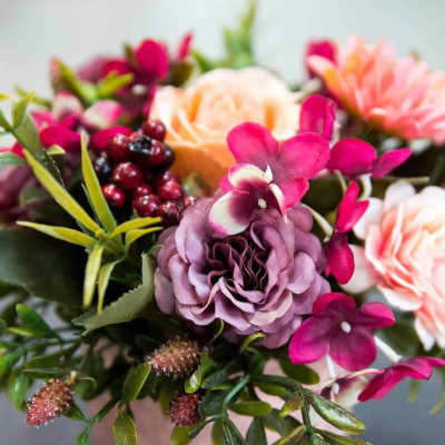 Pink and peach floral arrangement in a pale vase