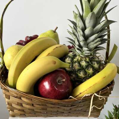 Fruit basket with bananas, pineapple, apples, grapes, and pears