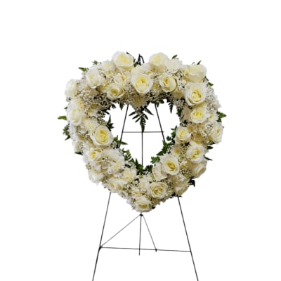 Heart-shaped white rose funeral wreath on a metal stand