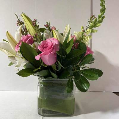 Pink roses and white lilies in a clear glass vase