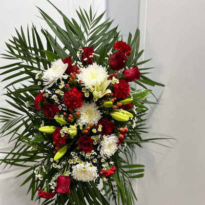 Standing floral spray with red and white flowers on a palm backdrop