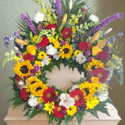 Colorful funeral wreath with sunflowers, roses, and lilies on a casket