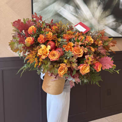 Large bouquet of orange roses with autumn leaves and red apples