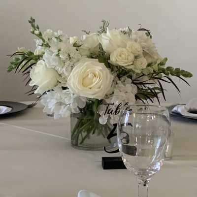 White rose centerpiece in a glass vase on a table