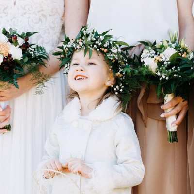 Child wearing a floral crown between two people holding bouquets