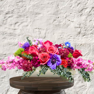 Bright mixed bouquet with pink and purple flowers in a low white container