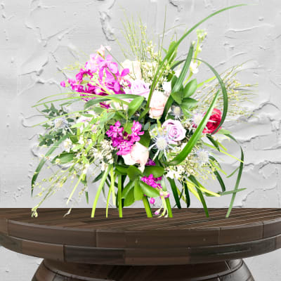 Pink and white mixed flower arrangement in a low wooden container
