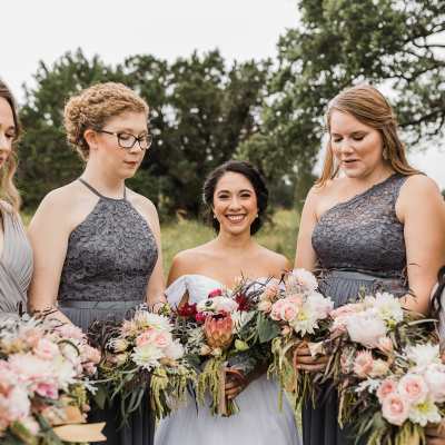 Bride and bridesmaids holding pastel wedding bouquets outdoors