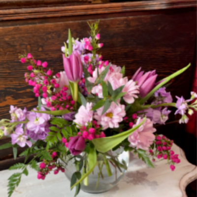 Pink and lavender flowers arranged in a clear glass vase