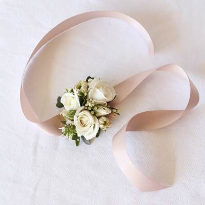 Small white rose corsage with pale pink ribbon on white fabric