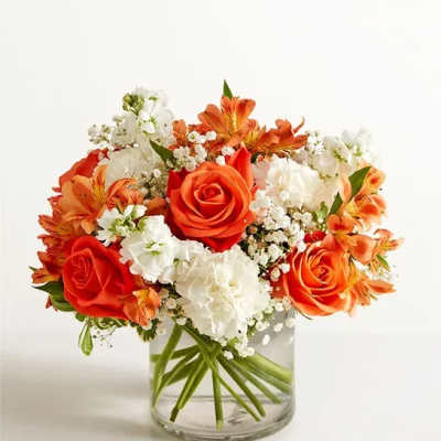 Orange and white roses arranged in a clear glass vase