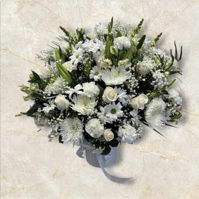 White floral arrangement in a ribbed vase with a ribbon