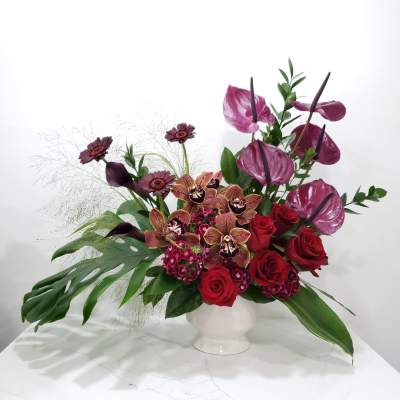 Red roses and purple orchids in a white vase