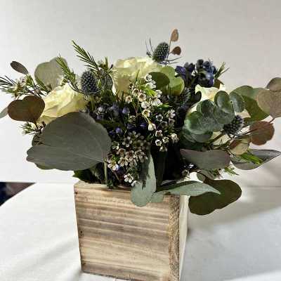 White roses and blue thistle in a wooden box arrangement