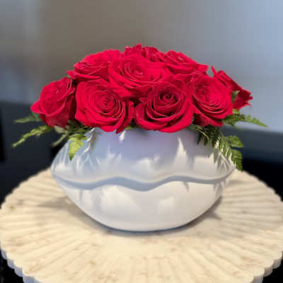 Red roses arranged in a white round vase