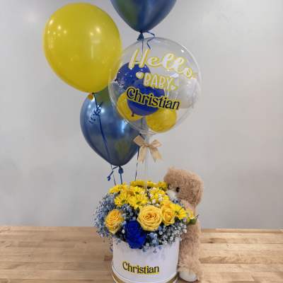 Blue and yellow flower hat box with baby-themed balloons and a teddy bear.