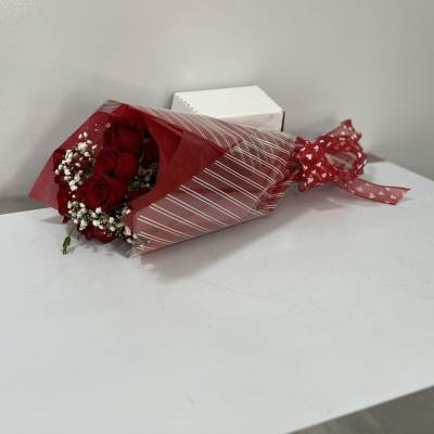 Bouquet of red roses wrapped in red paper with white baby's breath