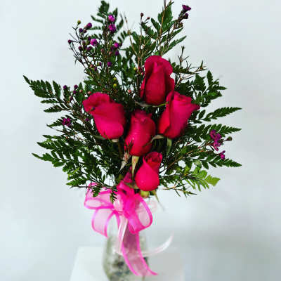 Pink roses in a clear glass vase with a pink ribbon