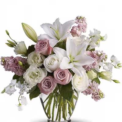 Bouquet of white lilies, roses, and pink flowers in a clear glass vase