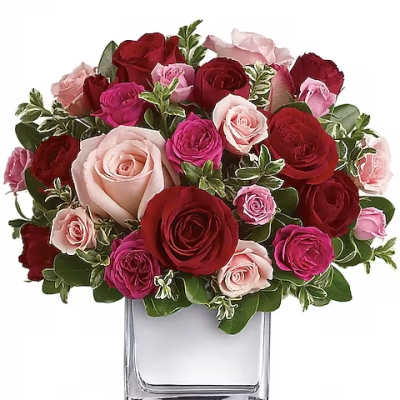 Bouquet of red, pink, and blush roses in a clear glass vase
