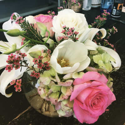 Pink and white floral arrangement with roses, tulips, and calla lilies in a glass vase