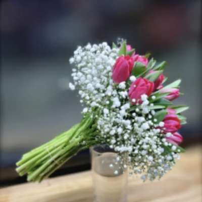 Pink tulip bouquet with baby's breath in a clear glass vase