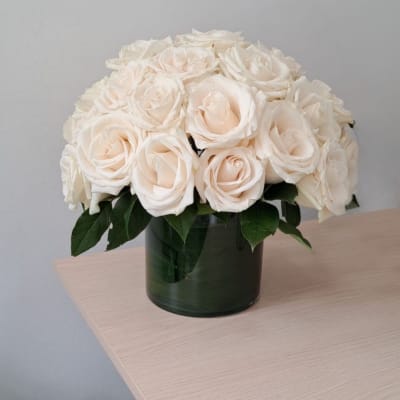 Cream rose bouquet in a dark glass vase
