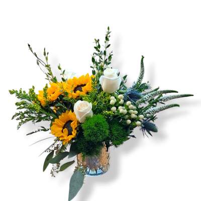 Sunflowers and white roses in a glass vase with greenery