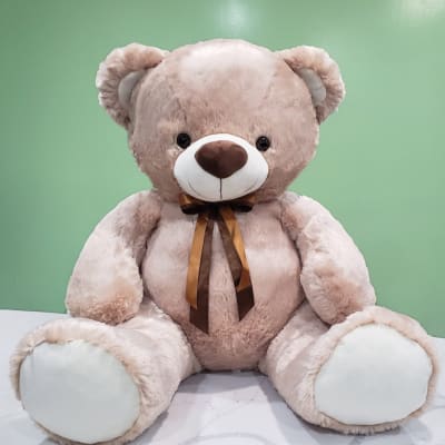 Large beige teddy bear with a brown ribbon bow