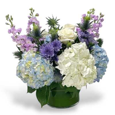 Bouquet of hydrangeas, roses, and purple flowers in a glass vase