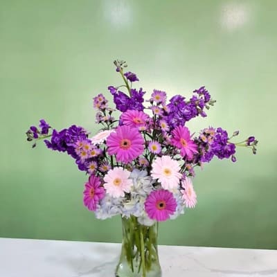 Pink and purple daisy bouquet in a clear glass vase