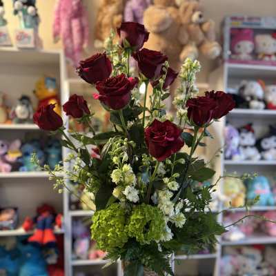 Red roses and white flowers in a purple glass vase