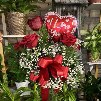 Red roses in a glass vase with a heart balloon and red ribbon
