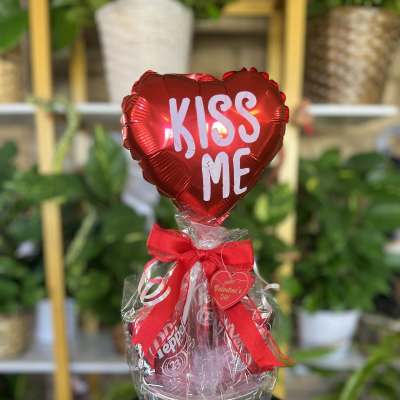 Heart-shaped red balloon above a gift bucket with soda cans and a red bow