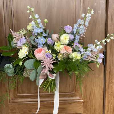 Hand-tied bouquet of pastel flowers with long white ribbons