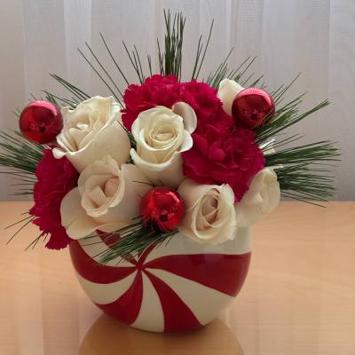 White roses and red carnations in a red-and-white vase with red ornaments
