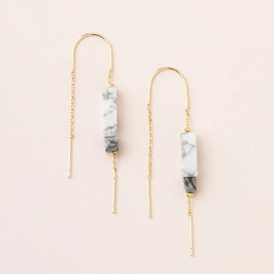 Pair of gold threader earrings with white marbled rectangular stones on a light background